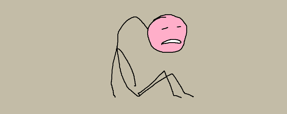 A person sits hunched on the floor, looking sad