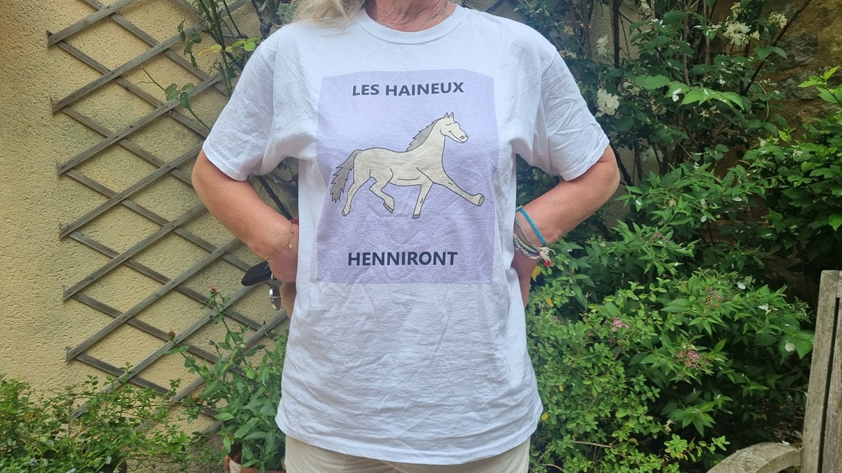 A person wearing a t-shirt with a horse and the texte "LES HAINEUX HENNIRONT"
