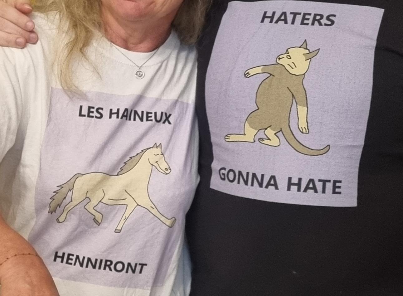Two people wearing t-shirts, one has a horse saying "LES HAINEUX HENNIRONT", one has a cat saying "HATERS GONNA HATE"