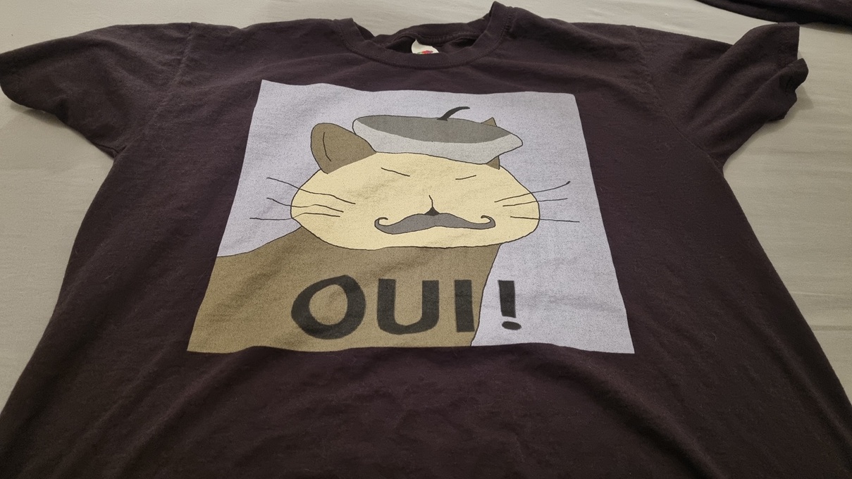 A t-shirt of a cat wearing a beret with the text "OUI!"