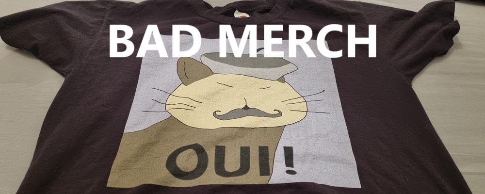 A t-shirt of a cat wearing a beret saying OUI!, under the text BAD MERCH